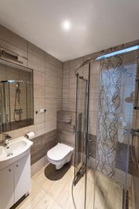 ein Bad mit einer Dusche, einem WC und einem Waschbecken in der Unterkunft Apartamenty HELJAN in Międzywodzie