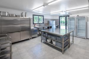a large kitchen with stainless steel appliances and a table at Gite de la Gandonnière - Au pied du circuit des 24hr, pour 10 à 31 personnes in Teloché