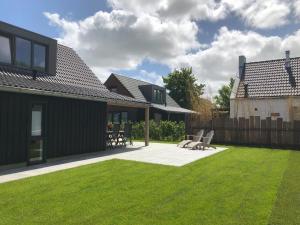 a backyard with a lawn and a house at Bungalow 74 op Recreatiepark De Wielen in Sint Maarten