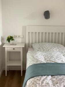 1 dormitorio con cama y mesita de noche blanca con cama sidx sidx sidx sidx en Landhaus Tipp en Altenmedingen