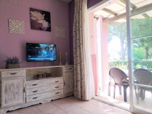 uma sala de estar com uma televisão num armário e uma janela em Magnífico adosado de esquina con vistas al golf playas Islantilla em Islantilla