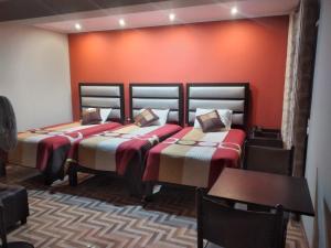 2 Betten in einem Zimmer mit orangefarbener Wand in der Unterkunft Gavina Inn Hotel in Tacna
