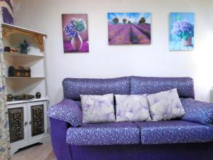 un sofá púrpura en una sala de estar con pinturas en la pared en Magnífico adosado de esquina con vistas al golf playas Islantilla, en Islantilla