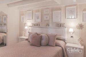 a white bedroom with a bed with pink pillows at Masseria Fabula Bistrot & Maison in Monopoli