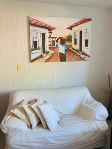 a painting hanging on a wall above a couch at condominio moradas de guarajuba in Guarajuba