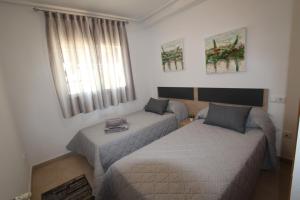 Habitación pequeña con 2 camas y ventana en Adosado Roldán by Rental Olé, en Roldán