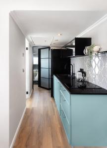 a kitchen with blue cabinets and a black counter top at Seaview Stylish Apartment with Balcony in Herzelia 
