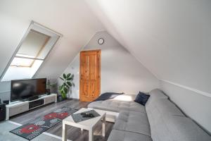 a living room with a couch and a tv at Buzavirág Apartman in Keszthely