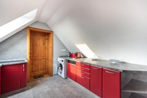 an attic kitchen with red cabinets and a washing machine at Buzavirág Apartman in Keszthely