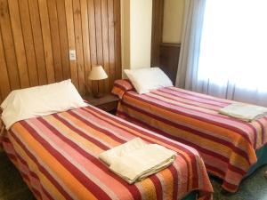 two beds sitting next to each other in a room at Hotel Mustapic in Ushuaia