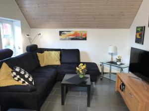 ein Wohnzimmer mit einem schwarzen Sofa und einem TV in der Unterkunft Sonnendeck in Greetsiel
