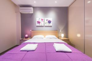 purpurowa sypialnia z dużym łóżkiem i 2 białymi ręcznikami w obiekcie An Impressive 2 bdr Apt in Glyfada w Atenach