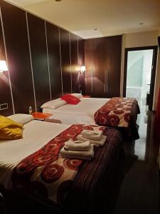 two beds in a hotel room with towels on them at Hostal Alcalá Del Jucar in Alcalá del Júcar