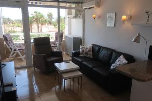 a living room with a black leather couch and a table at Sunny Apartment Teneguia by Yumbo in Playa del Ingles