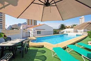 a pool on the roof of a building with tables and umbrellas at Villa Calalga - PlusHolidays in Calpe