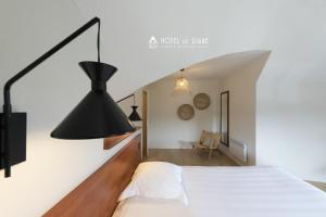 ein Schlafzimmer mit einem weißen Bett und einer schwarzen Lampe in der Unterkunft Hotel De Diane in Sables-dʼOr-les-Pins