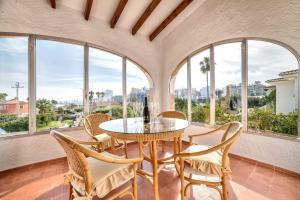 a dining room with a table and chairs and windows at Villa Benicolada - PlusHolidays in Calpe