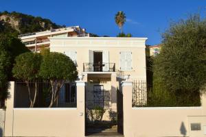 a white house with a gate and trees at Villa - Climatisé -Vue mer - Proximité des plages in Villefranche-sur-Mer