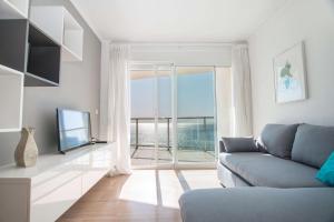 a living room with a couch and a large window at Apartamento Barlovento - PlusHolidays in Calpe