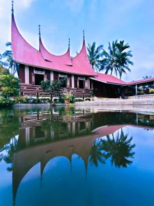 a building with a red roof reflected in the water at Rumah Gadang Simarasok in Baso