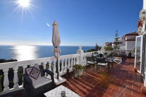 un balcón con una mesa y una sombrilla y el océano en Ladera Panorama 2 en Nerja