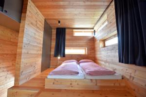 two beds in a wooden room with two windows at Design Lodge The Cube in Ortisei