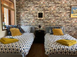 a bedroom with two beds and a brick wall at le bout du Bout in Les Arques