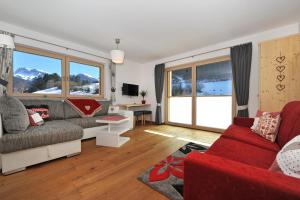 a living room with a red couch and windows at Apartments Cesa Leni in Ortisei