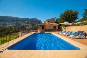 a swimming pool with chairs and a house at Villa Bou - PlusHolidays in Calpe