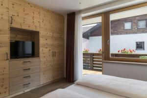 a bedroom with a bed and a tv and a window at Apartments Jalve in Ortisei