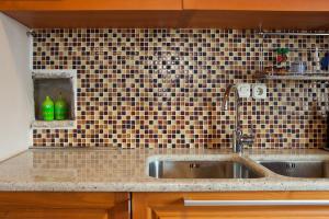 a kitchen with a sink and a tiled wall at Studio Zavala in Zavala