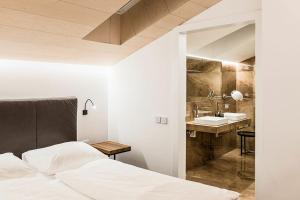 a bedroom with a bed and a bathroom with a sink at Apartments Rumanon in Ortisei