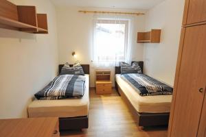 two beds in a small room with a window at Apartments Villa Jim in Ortisei