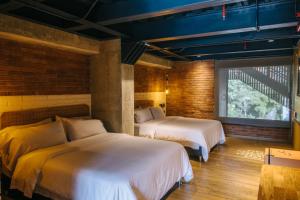 1 dormitorio con 2 camas y pared de ladrillo en The Somos Beats Hotel & Rooftop, en Medellín