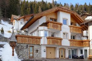 a house with wooden balconies on a mountain at Apartments Mujnei in Santa Cristina Gherdëina