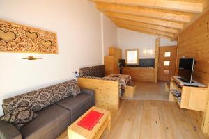 ein Wohnzimmer mit einem Sofa und einem TV in der Unterkunft Mountain Apartment Hapeli in St. Ulrich in Gröden
