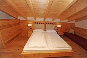 a large bed in a room with wooden ceilings at Mountain Apartment Hapeli in Ortisei
