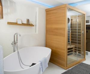 La salle de bains est pourvue d'une baignoire blanche et d'une armoire en bois. dans l'établissement Rain Apartment with private spa area-Zorten-Lenzerheide, à Obervaz
