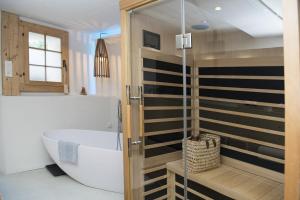 La salle de bains est pourvue d'une baignoire et d'une douche. dans l'établissement Rain Apartment with private spa area-Zorten-Lenzerheide, à Obervaz