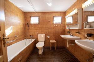 La salle de bains est pourvue d'une baignoire, de toilettes et d'un lavabo. dans l'établissement Ferienhaus Alvaneu für Familien, à Alvaneu