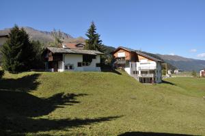 a house on top of a grassy hill at Ski in-Ski out Apartment Heimberg-Parpan-Lenzerheide in Parpan