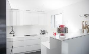a white kitchen with white cabinets and a counter at Ski in-Ski out Apartment Heimberg-Parpan-Lenzerheide in Parpan