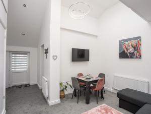 a white living room with a table and chairs at Beeches Bach in Prestatyn