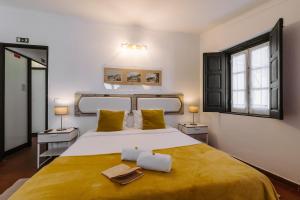 een slaapkamer met een groot bed met gele lakens bij Casa António Moreira in Óbidos