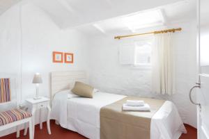 a white bedroom with a bed and a window at ROQUES 24 in Ciutadella
