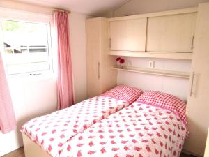 a bed in a small room with a window at Chalet 556 op Recreatiepark De Wielen in Sint Maarten +22 photos