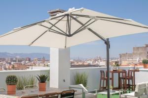 una sombrilla blanca en un patio con mesa y sillas en C77 - Romantic Studio in the Center with terrace, en Málaga