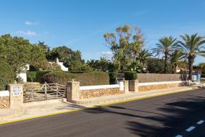 a street with a fence and trees on the side of a road at Brisa Mar 1, 2 bedroom apartment, Cala'n Bosch in Son Xoriguer