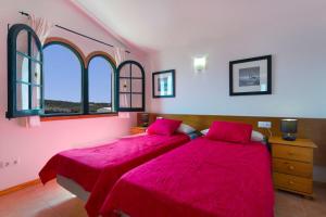 2 letti in una camera con lenzuola rosse e finestre di Villa Lira a Cala Morell Altre 19 foto