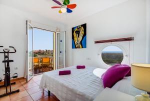 a bedroom with a bed with purple pillows and a window at Villa Fiesta in Ciutadella +4 photos